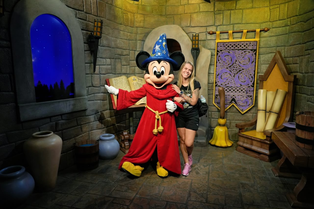 Thienne Giardino ao lado do Mickey Feiticeiro, personagem de Fantasia, no Magic Kingdom, em Orlando